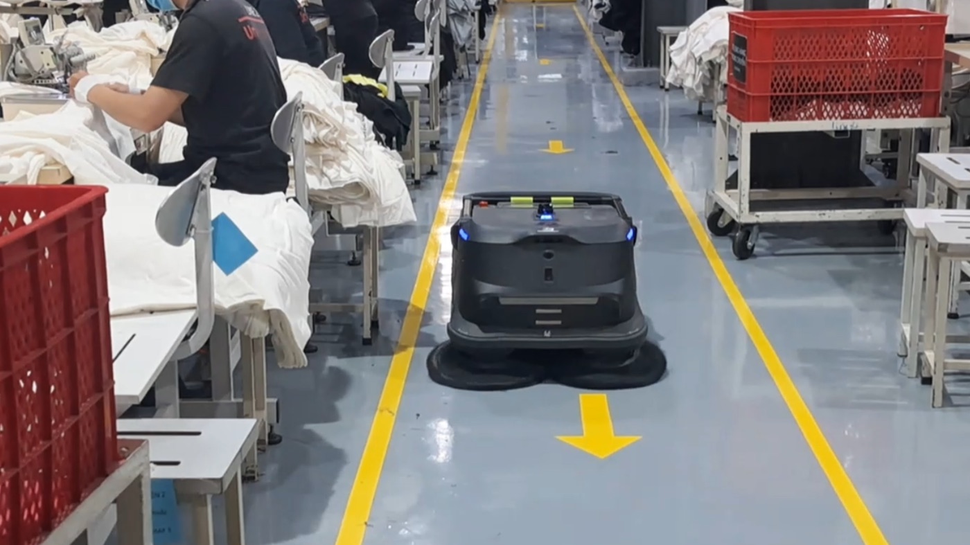 Robot nhà xưởng vận hành song song với công nhân trên lối đi giữa các chuyền