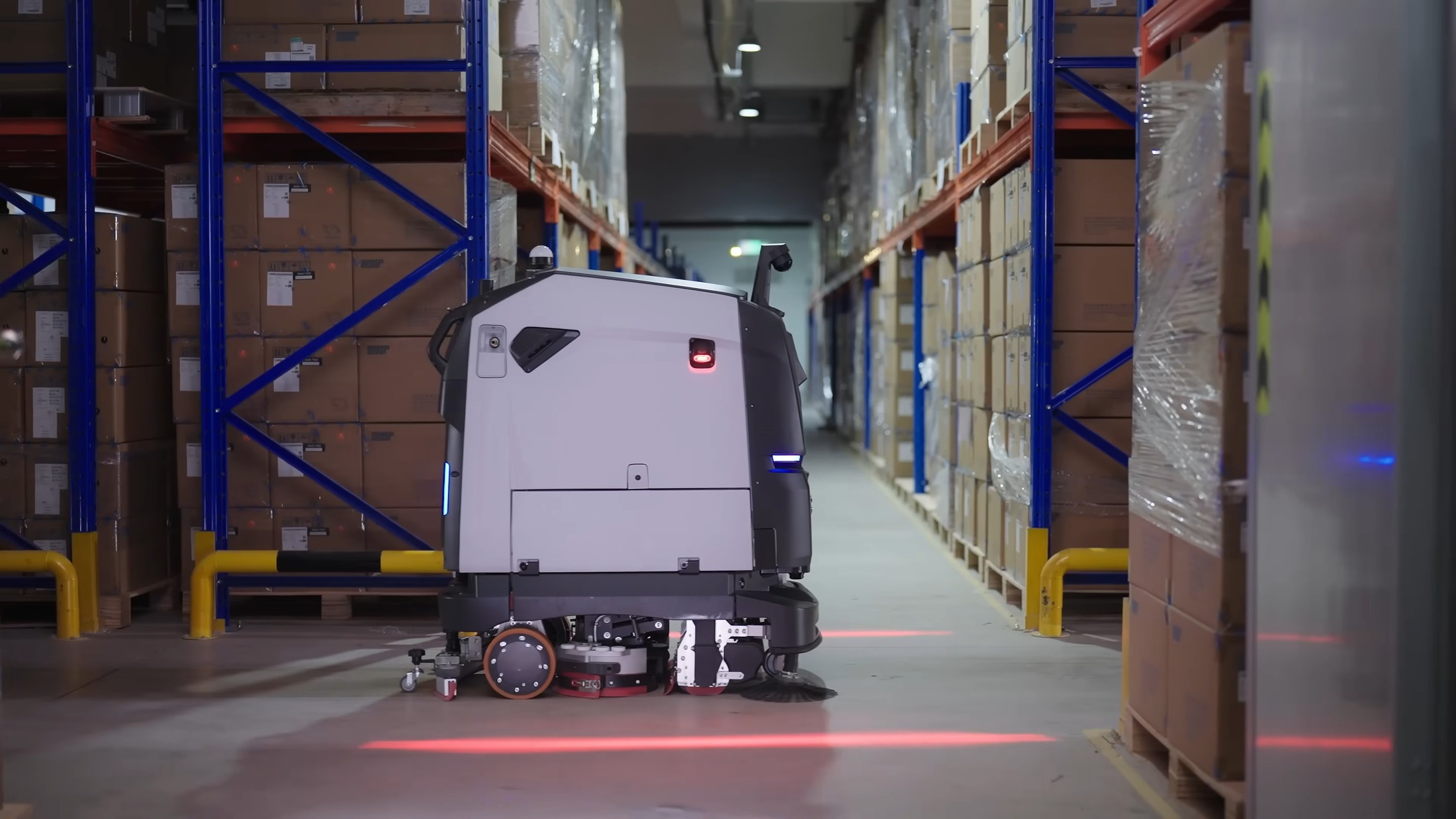 Robot vệ sinh công nghiệp làm sạch lối đi giữa các dãy giá kệ trong kho hàng