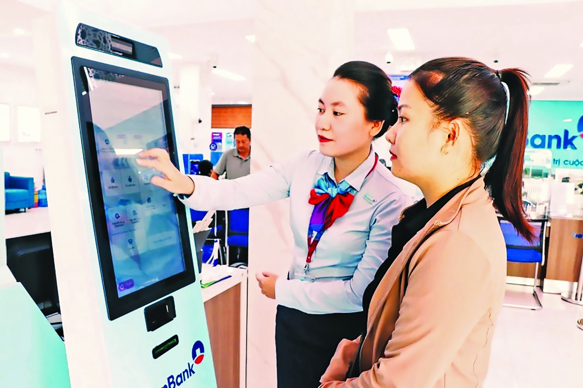 Nhân viên hướng dẫn khách hàng dùng quầy giao dịch tự động tại ngân hàng