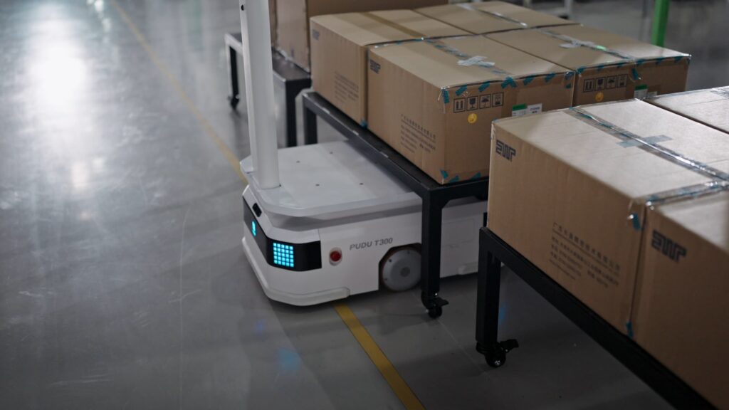 Robot giao hàng nhà máy kéo xe hàng chở thùng carton trong xưởng sản xuất