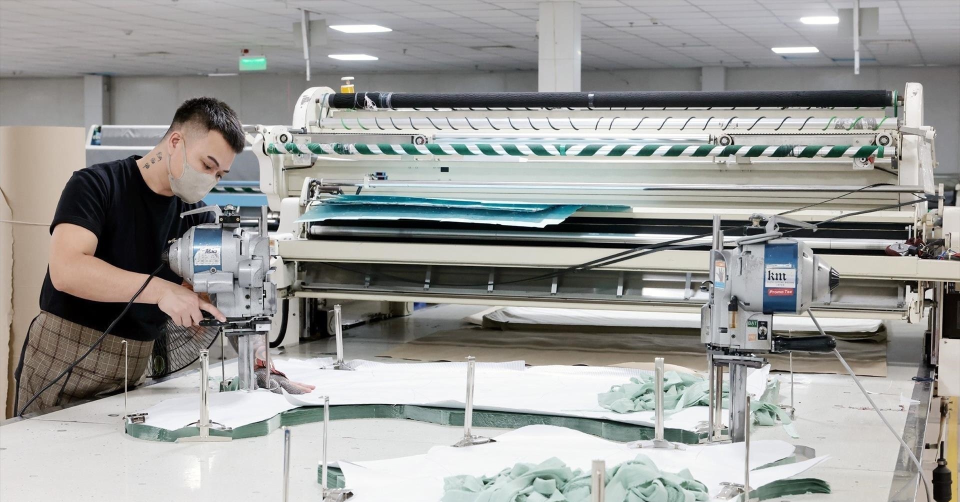 Máy trải vải và dao cắt đứng trong xưởng cắt