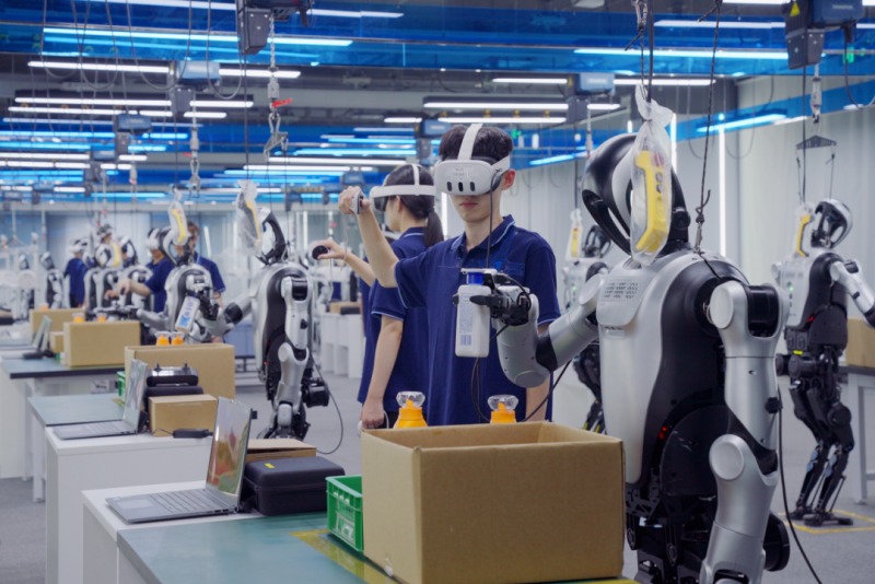 Người huấn luyện đeo kính thực tế ảo dạy robot hình người đóng gói hàng hóa