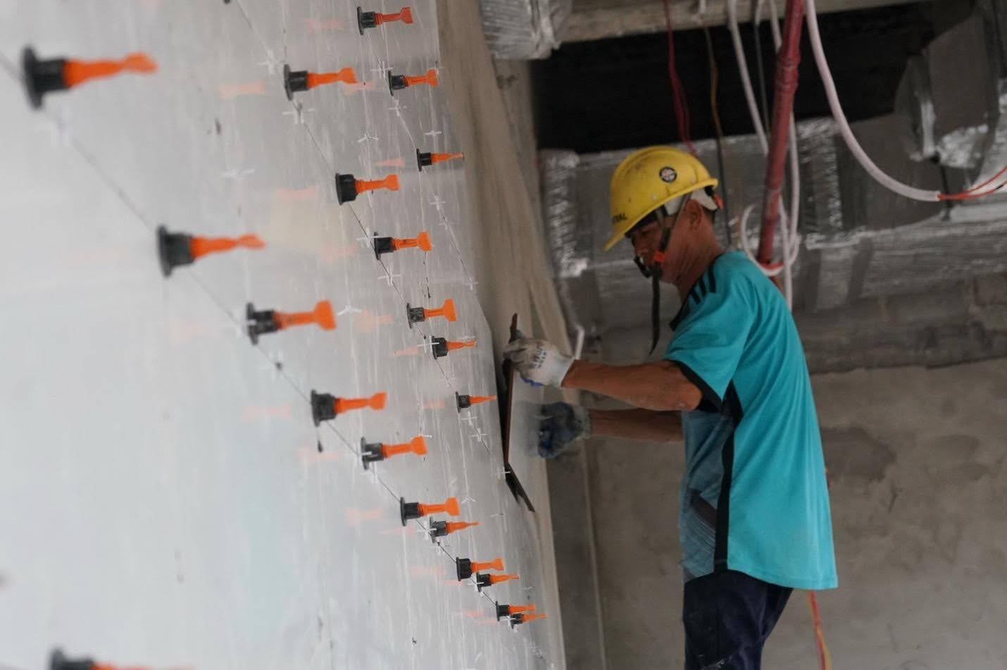 Thợ ốp gạch hoàn thiện tường khu sản xuất nhà máy suất ăn hàng không