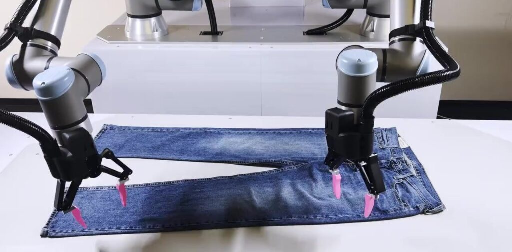 Robot hai tay của Sereact gấp quần jean trong quy trình xử lý hàng hoàn trả nhờ vòng lặp huấn luyện AI
